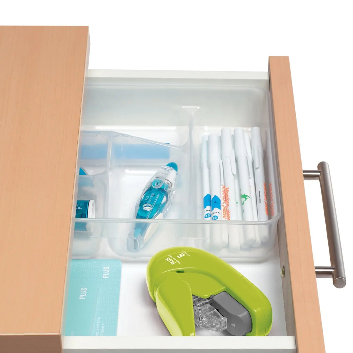 Green staple free stapler stored in a desk drawer with pens correction tape and other office supplies for organized everyday document fastening