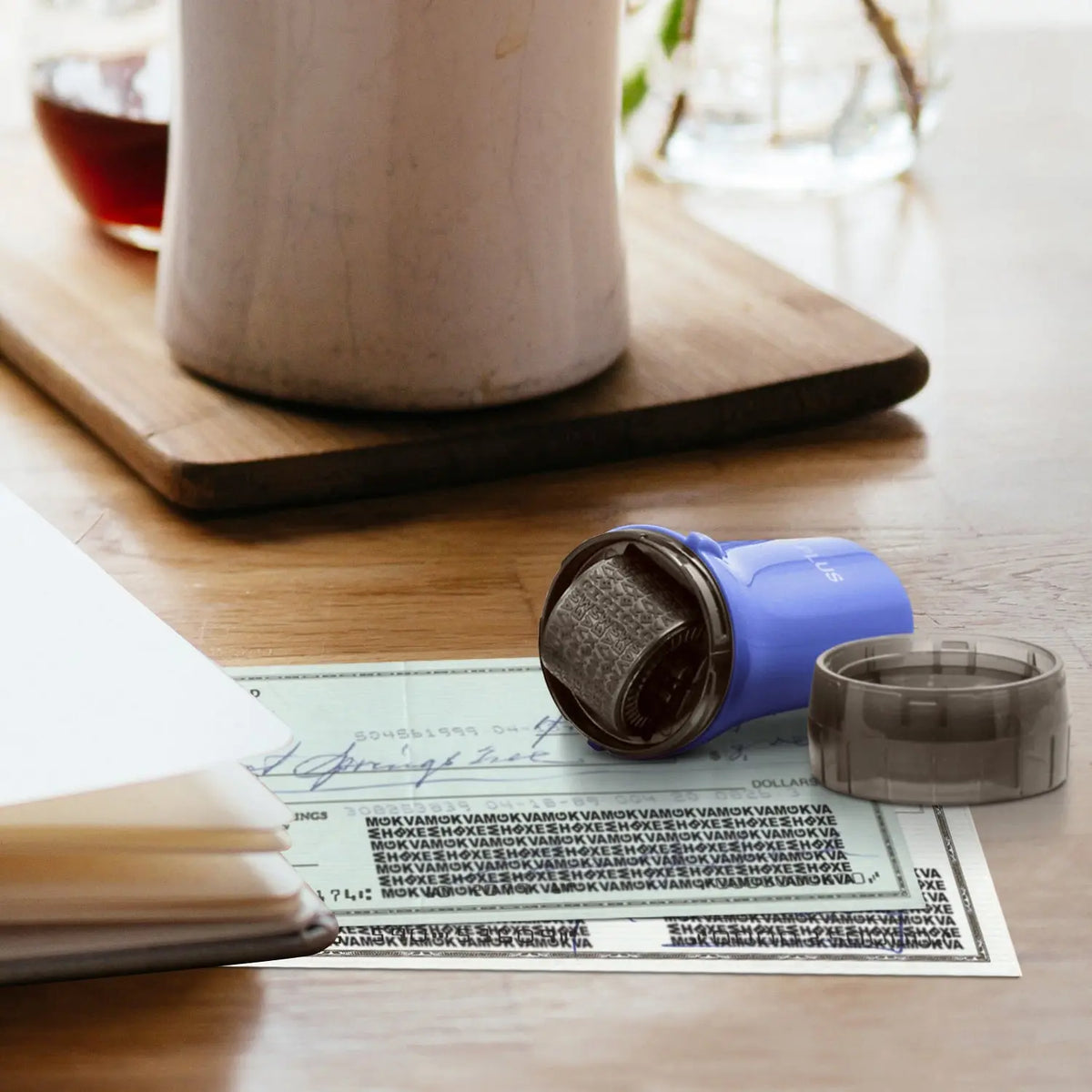 Blue privacy roller stamp covering personal information on a document beside paperwork on a wooden desk for everyday identity protection