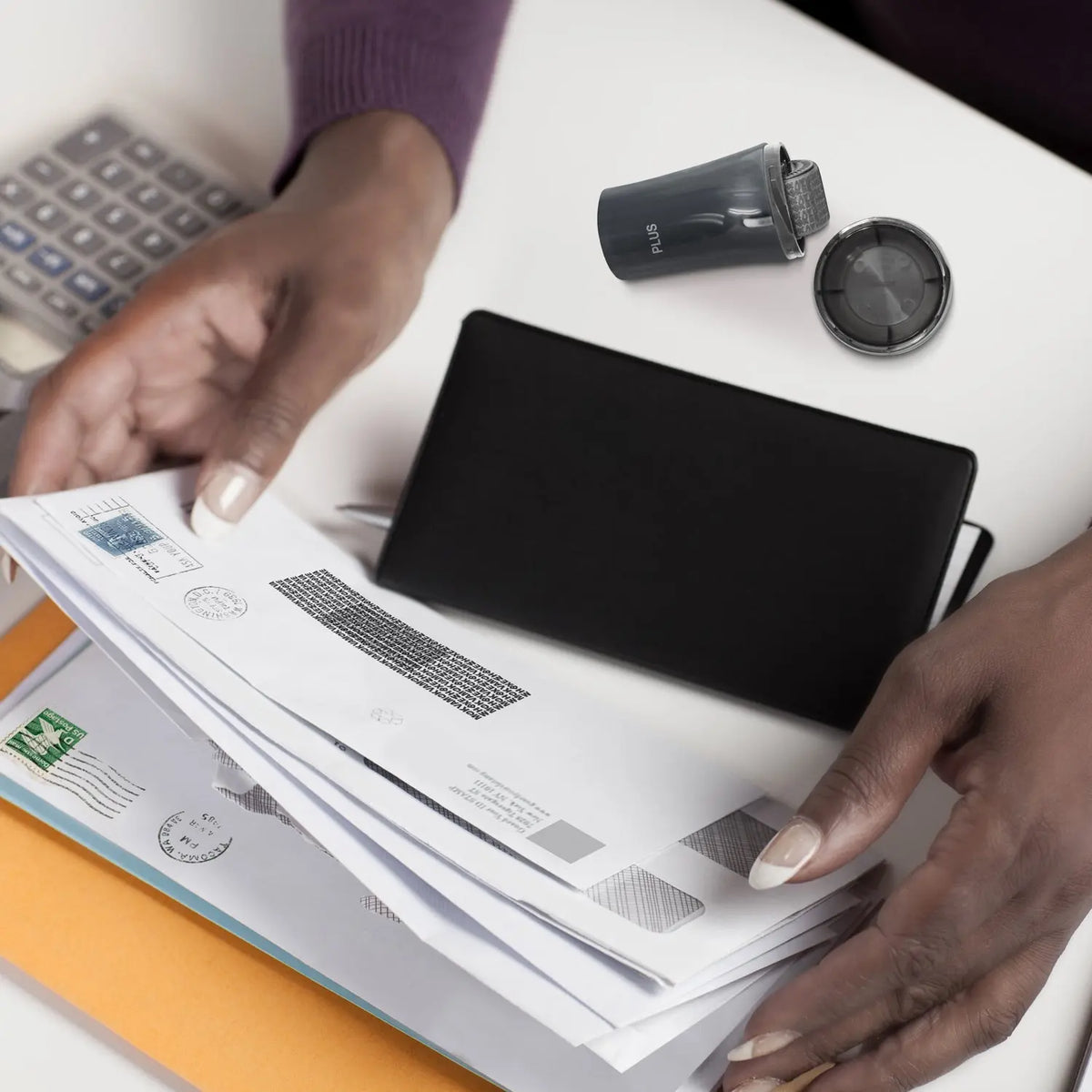 Compact privacy roller stamp beside mail and documents as hands sort letters helping cover names addresses and account details for everyday identity protection