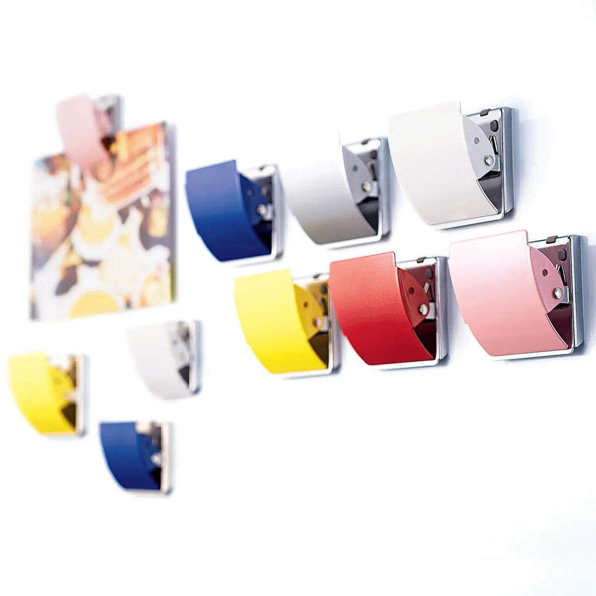Rubber-coated magnet clips holding papers on a metal surface