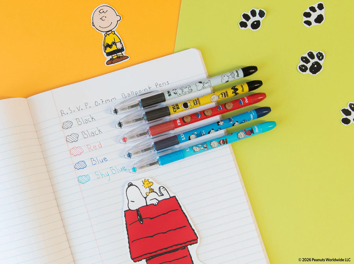 Five Peanuts themed Pentel RSVP ballpoint pens in assorted ink colors arranged on a lined notebook with a colorful Snoopy illustration
