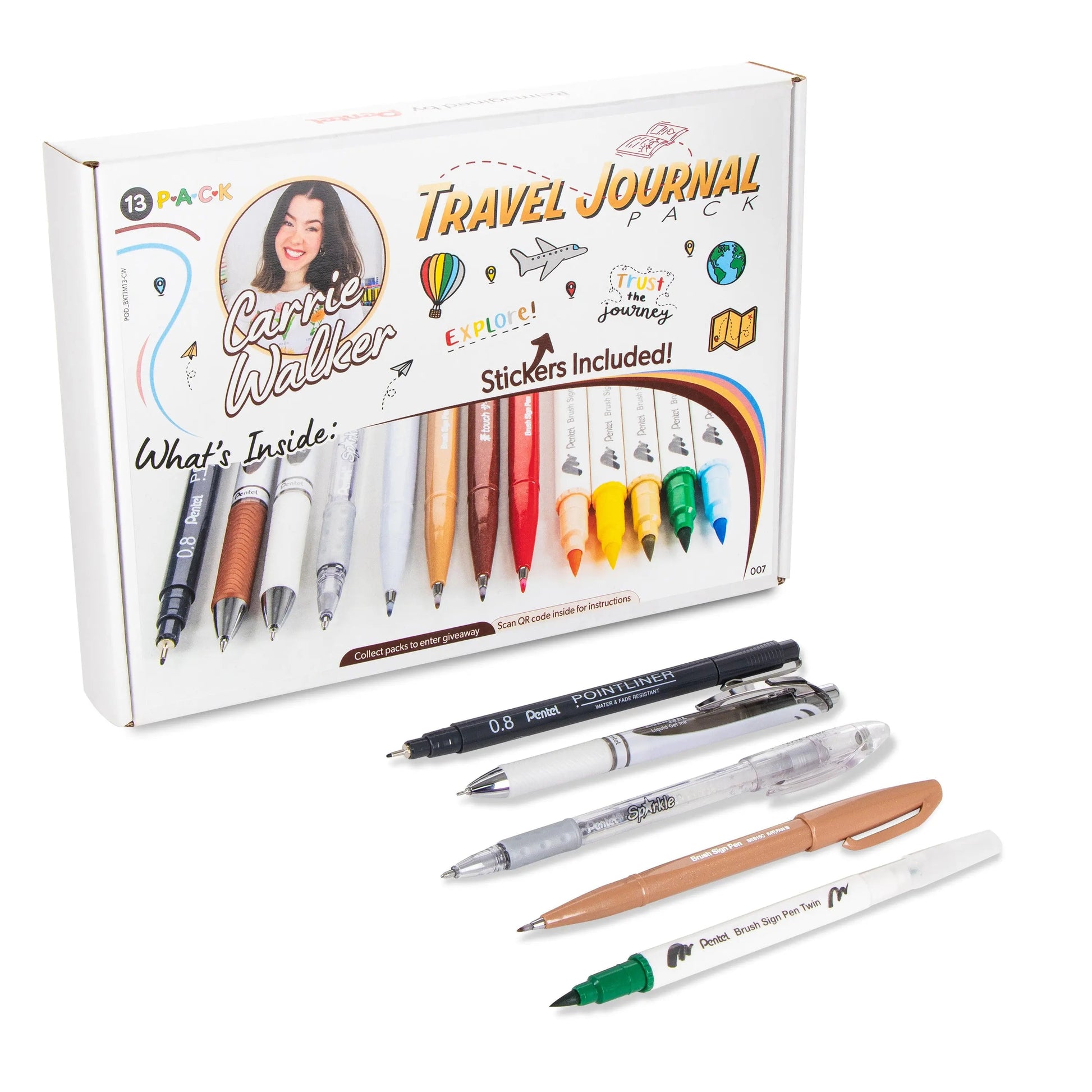 Set of assorted pens and markers in various colors displayed alongside a travel journaling pack box featuring stickers and travel-themed designs for creative journaling.