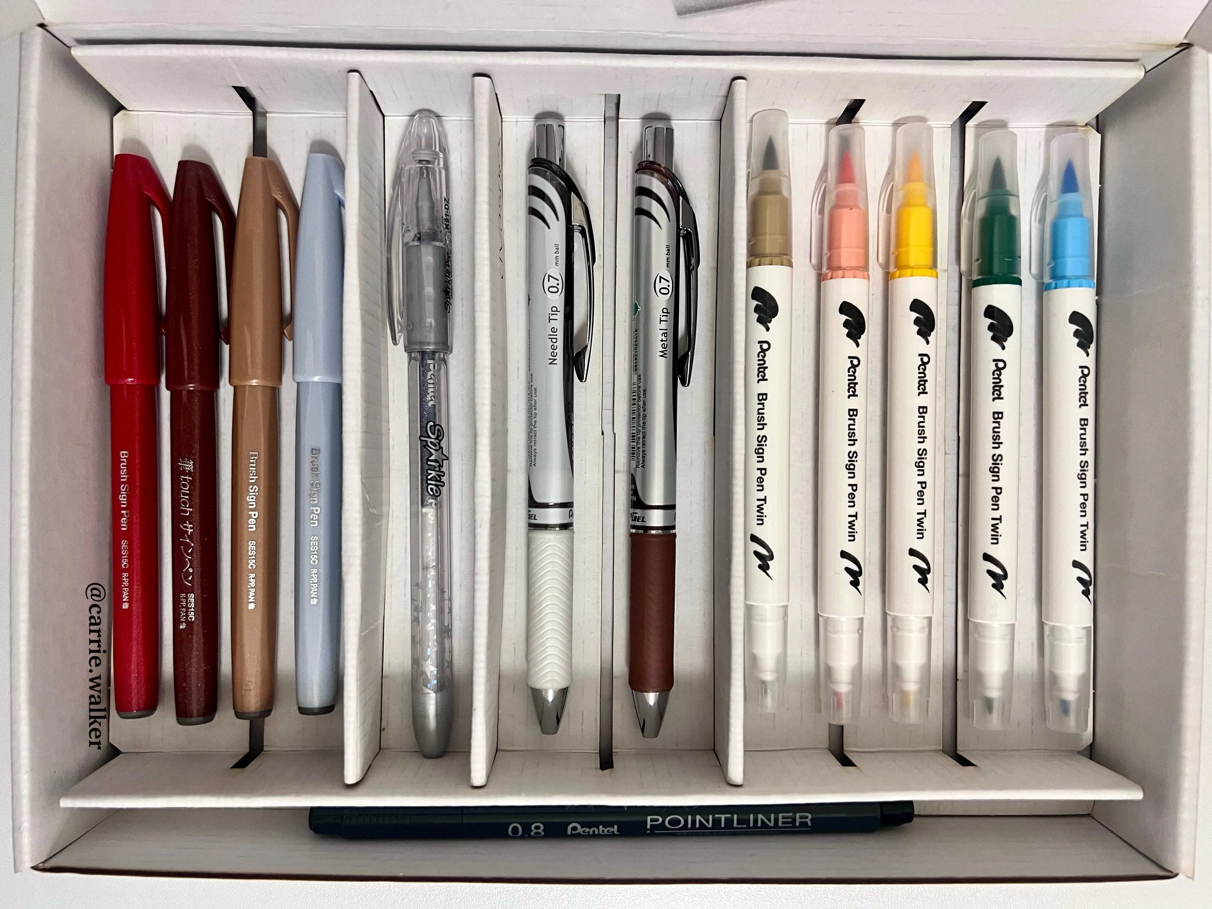 Set of colored gel pens, ballpoint pens, and brush pens arranged neatly in a box, ideal for journaling and artistic notes with vibrant ink options included.